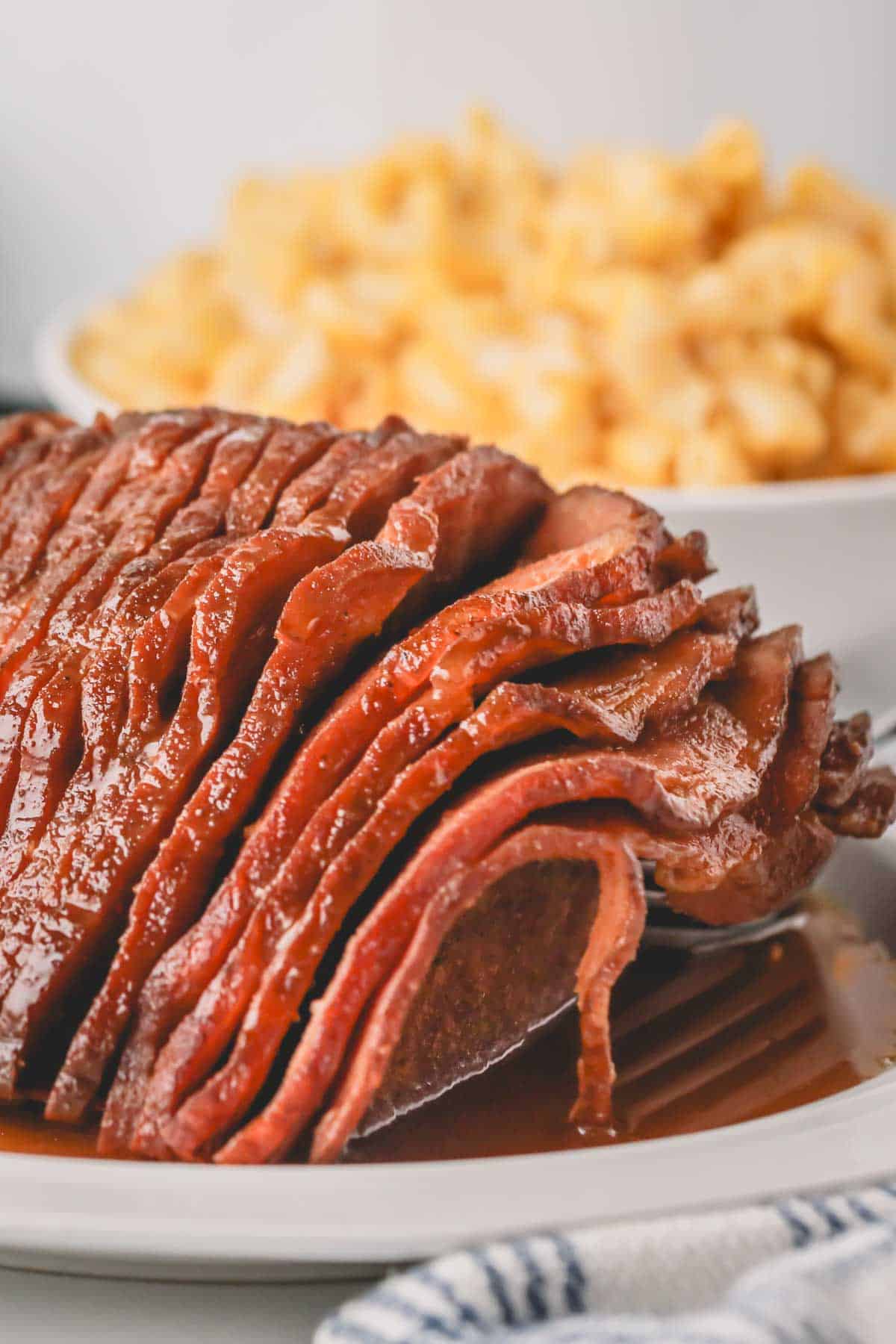 Close up of slow cooker honey glazed ham on a white plate.