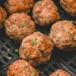 An air fryer basket with turkey meatballs.