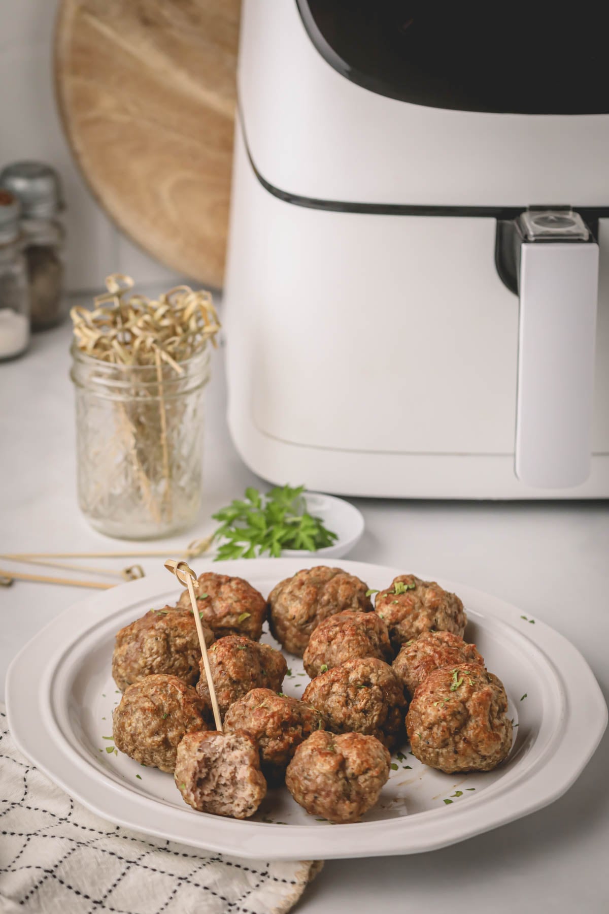 Air fryer turkey meatballs on a white plate with a white air fryer in the background.