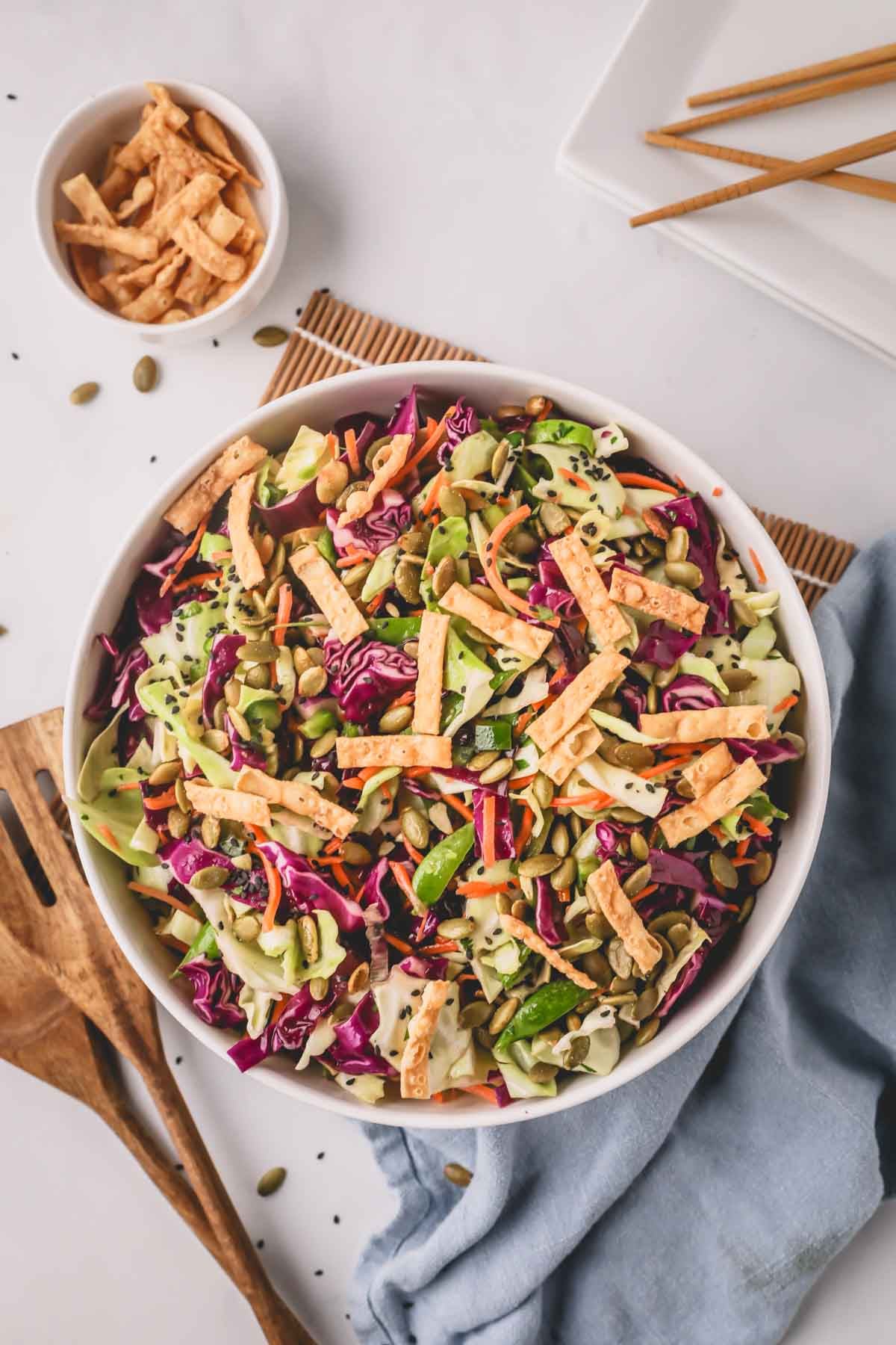 A white bowl with Asian slaw and a smaller white bowl with wonton strips.