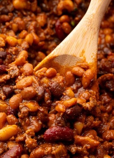 A wooden spoon scooping up cowboy baked beans.