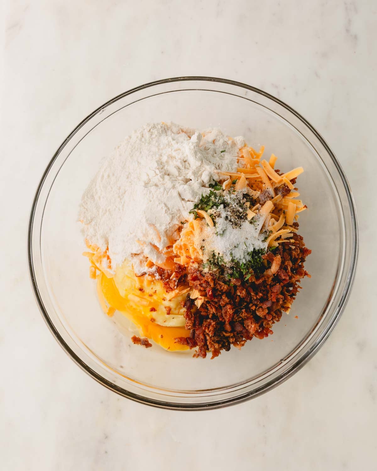 A glass bowl with ingredients for fried mashed potato patties.