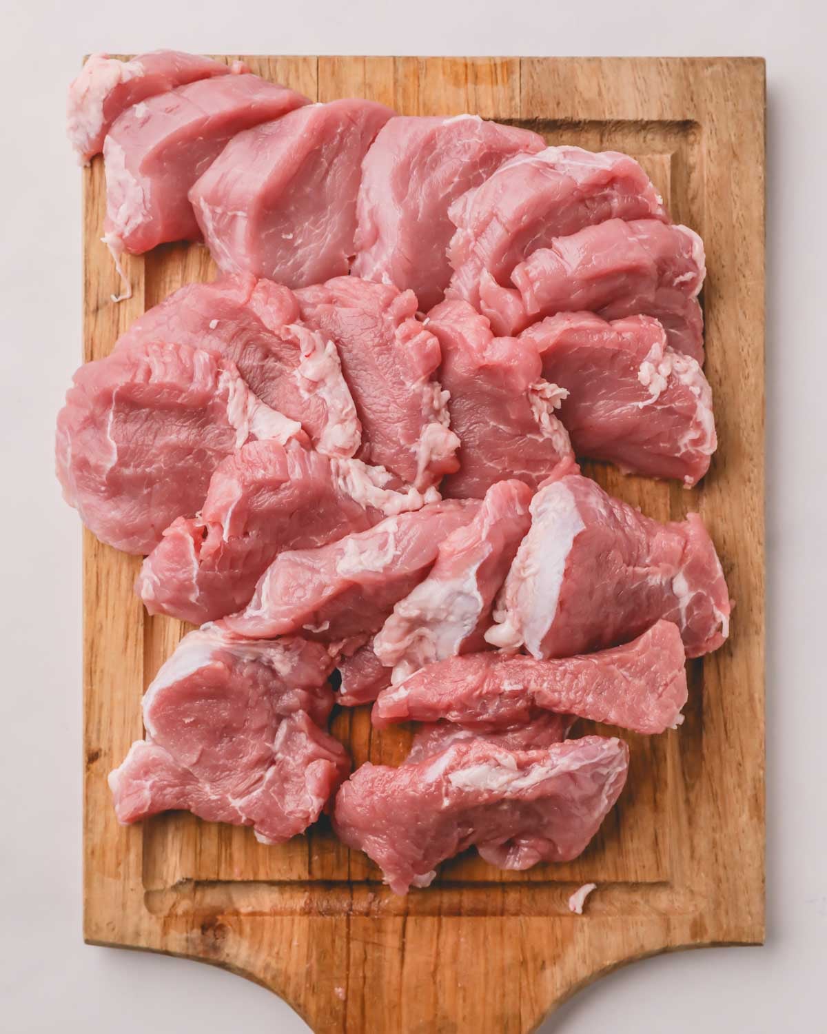 Pork tenderloin sliced on a wooden cutting board.