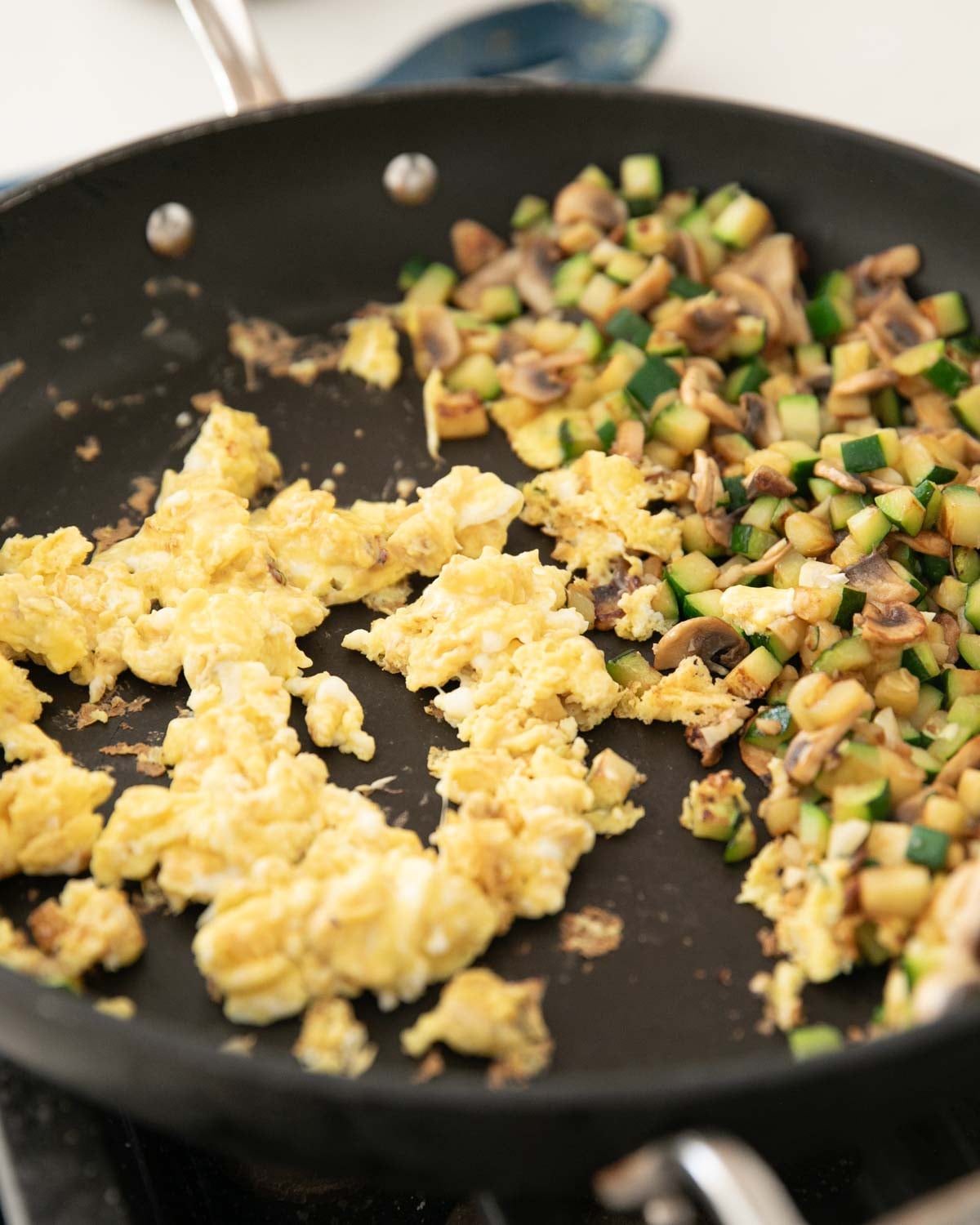 A skillet with zucchini, mushrooms, and eggs cooking.