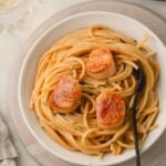 Scallop pasta in a white bowl with a black fork.