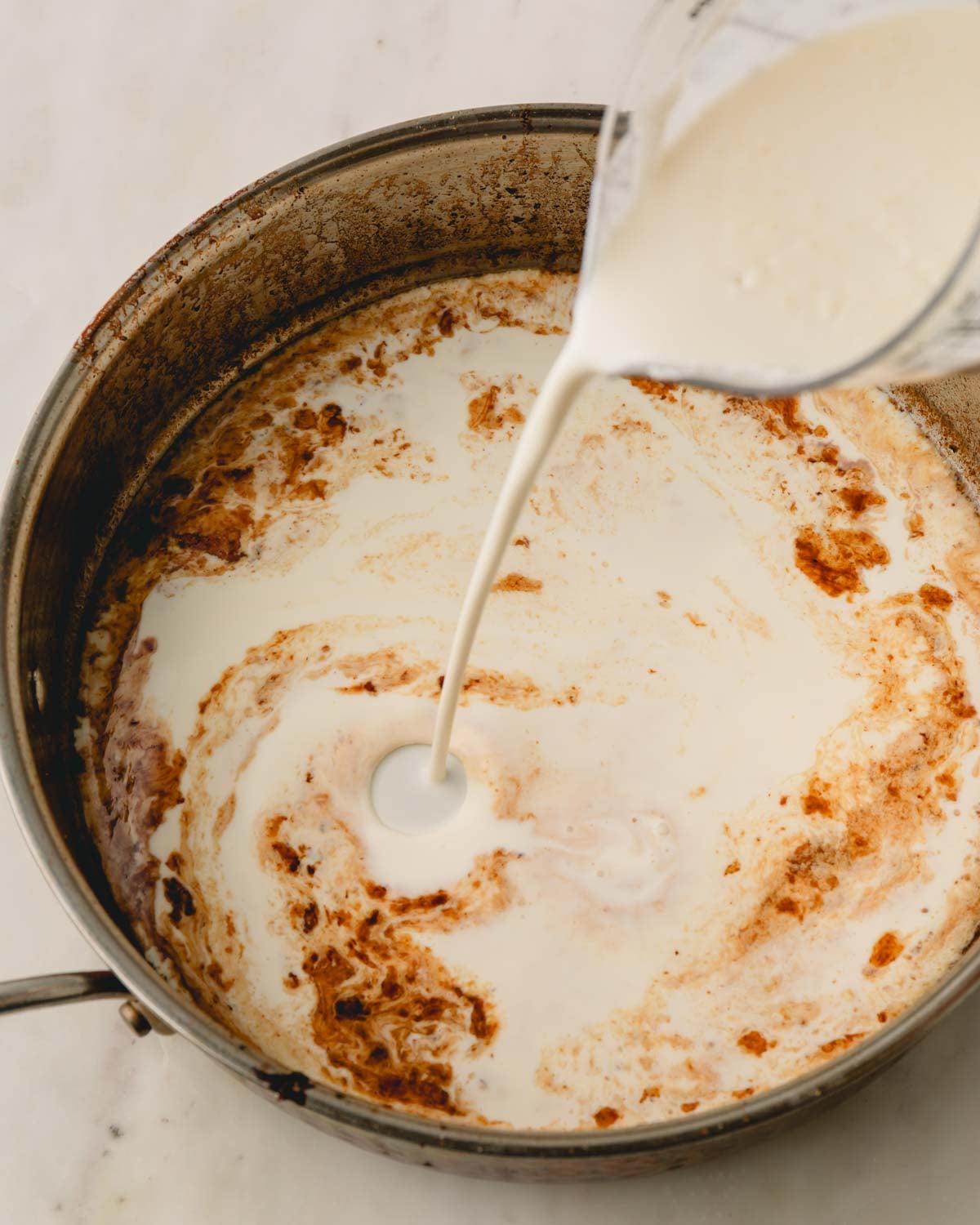 A skillet with cream being added for a pan sauce.