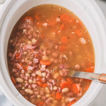 Overhead image of ham and beans in a slow cooker.