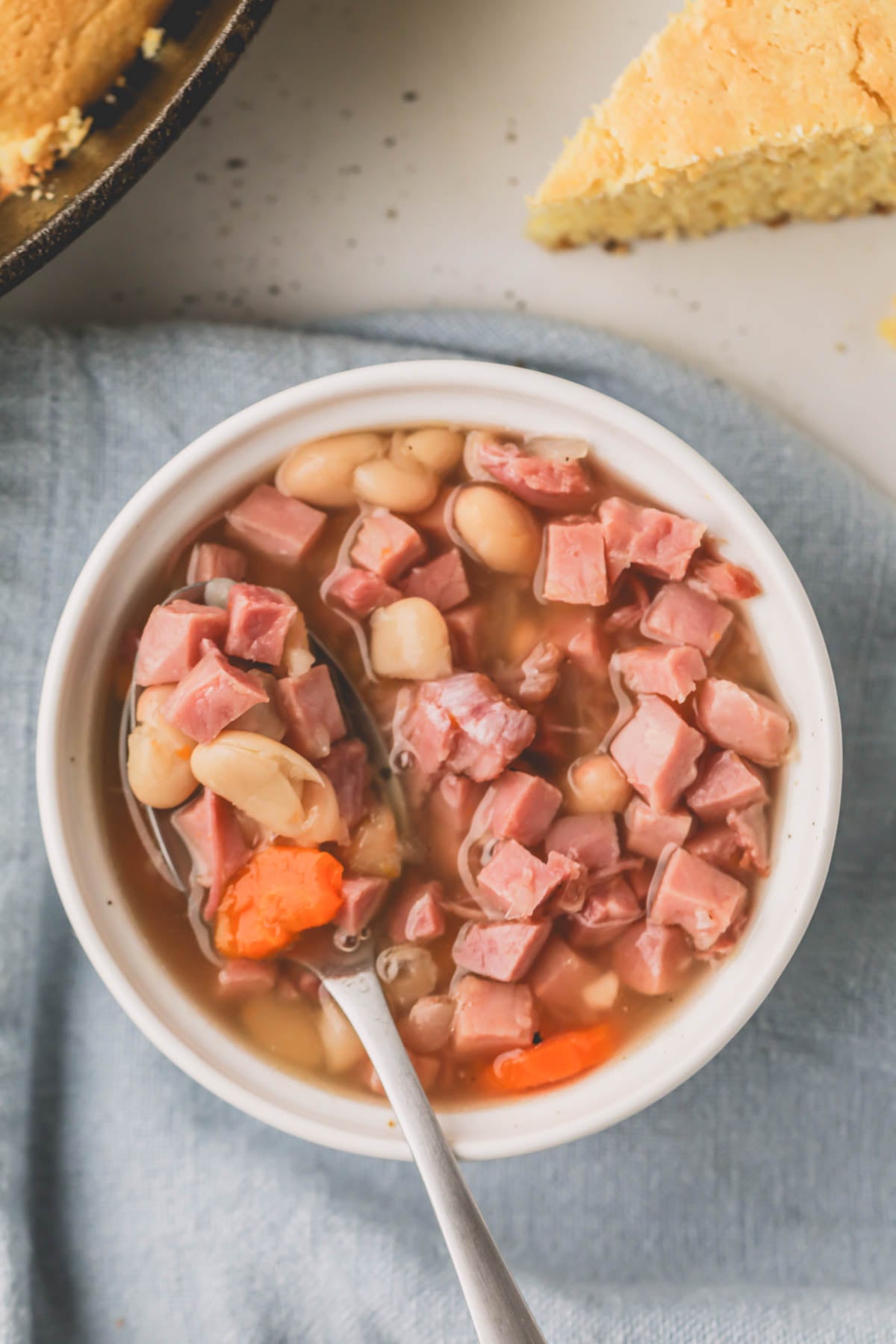 Overhead image of crockpot ham and beans in a white bowl.