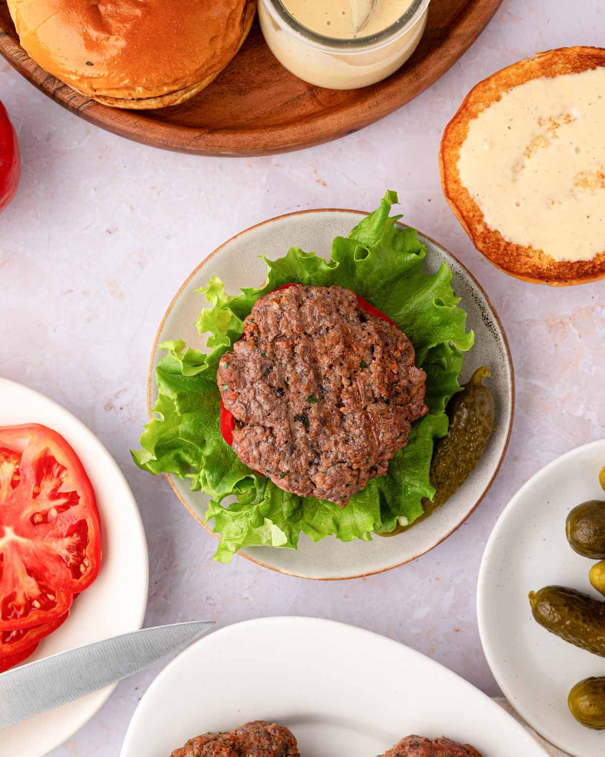 Overhead image of bison burger on a bun with lettuce and tomato on a gray plate.