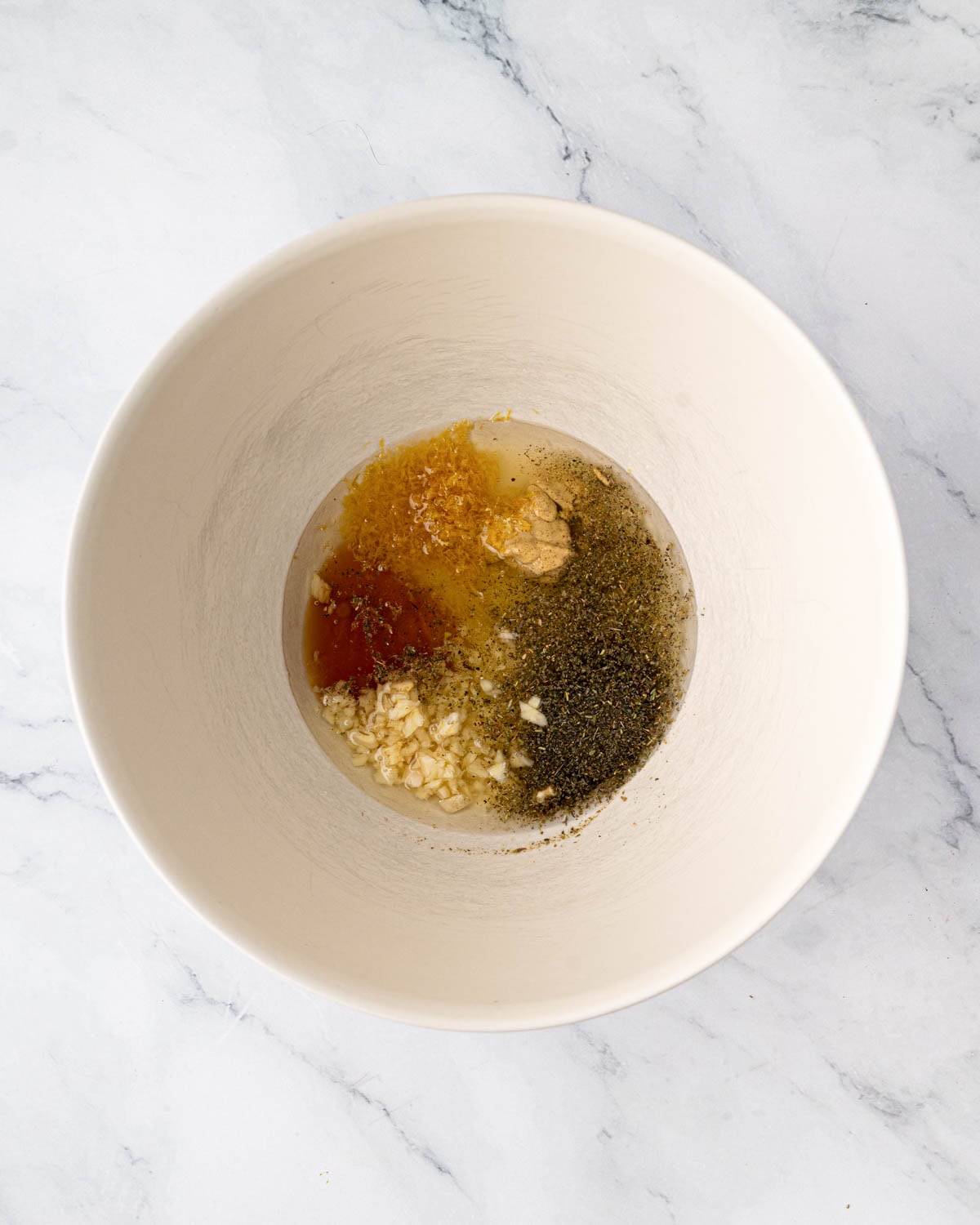 A white bowl with ingredients for lemon chicken marinade.