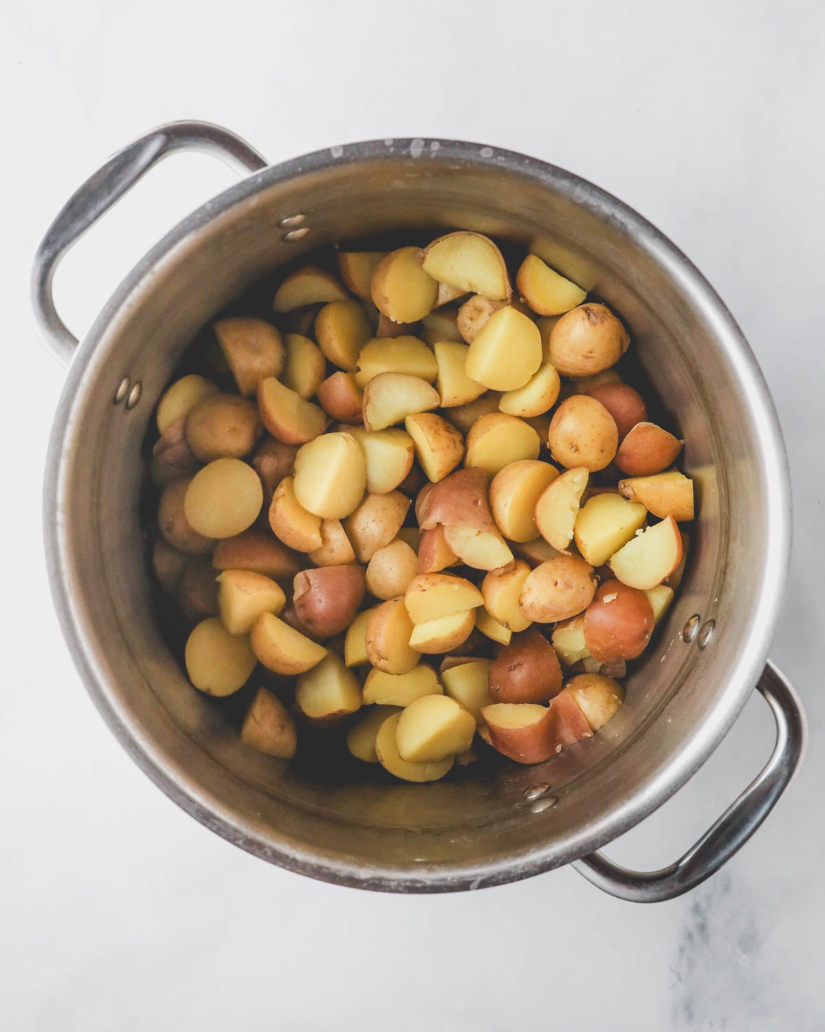 A pot with potatoes covered in water ready to boil.