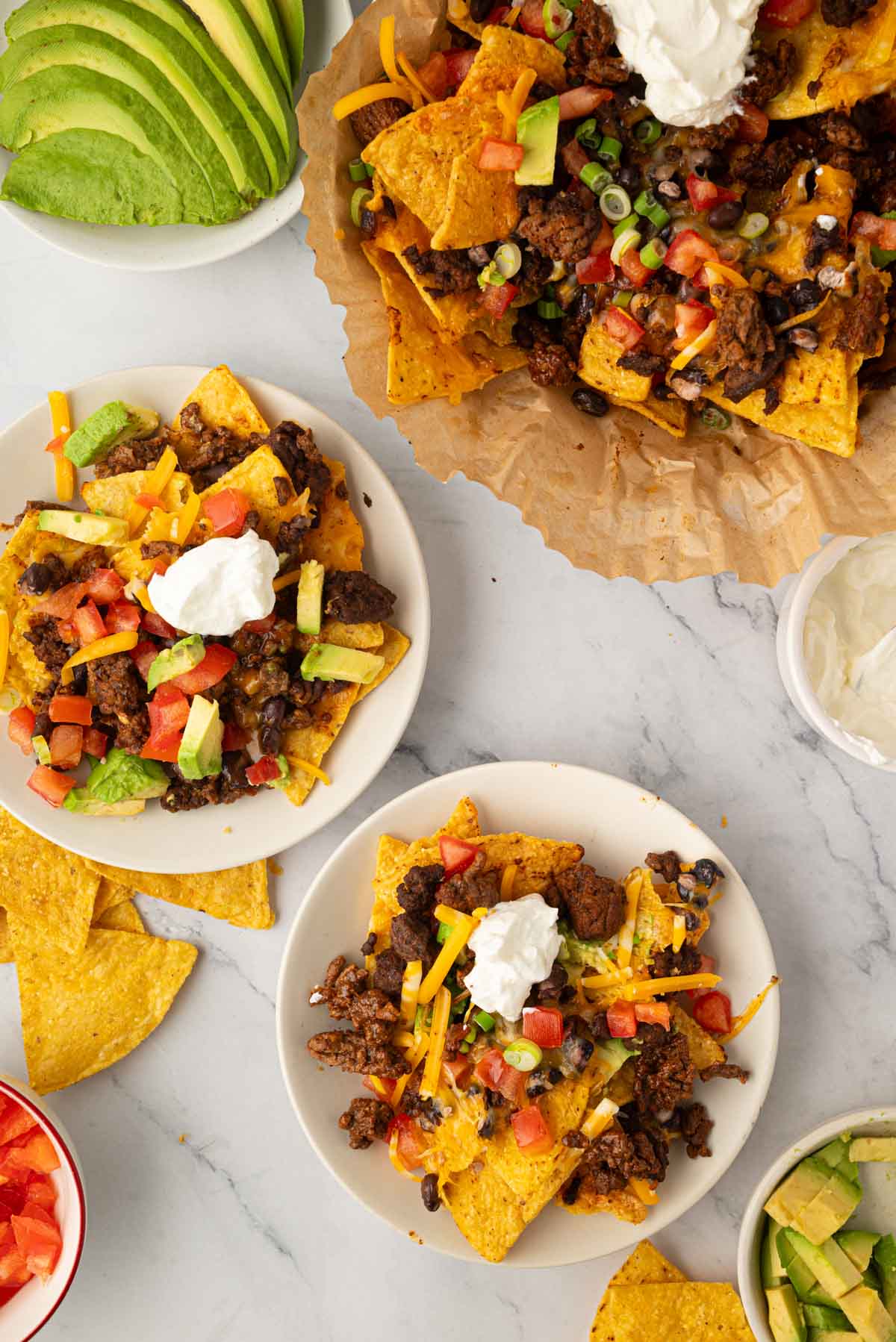 Overhead image of air fryer nachos on a plate with two smaller plates of nachos as well.
