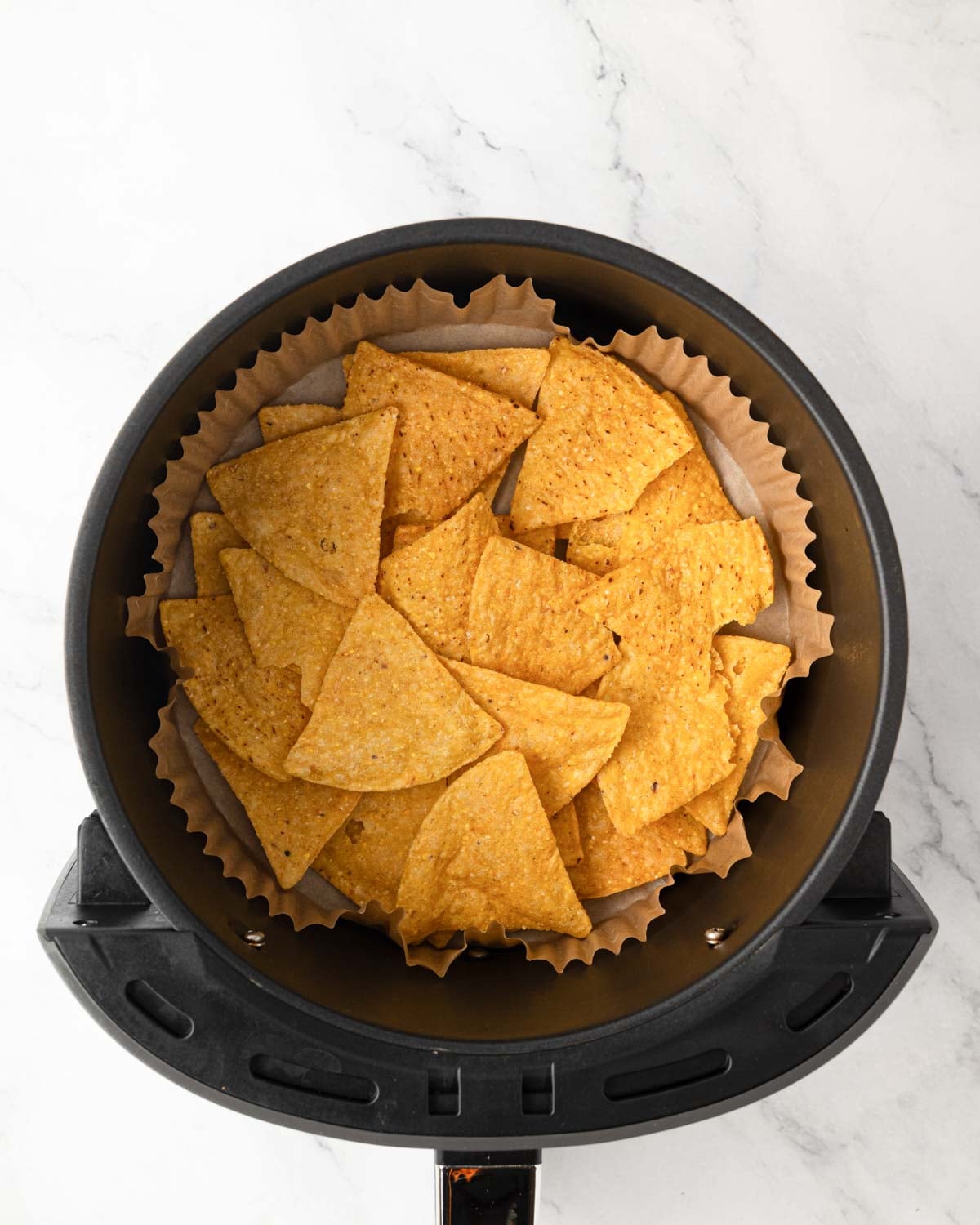 Air dryer basket with parchment paper and tortilla chips.