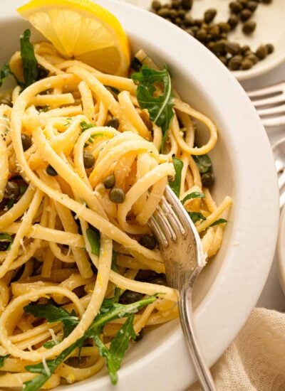 A white bowl with lemon caper pasta.