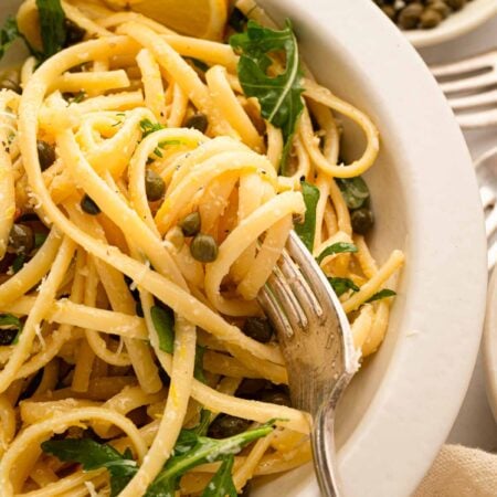 A white bowl with lemon caper pasta.