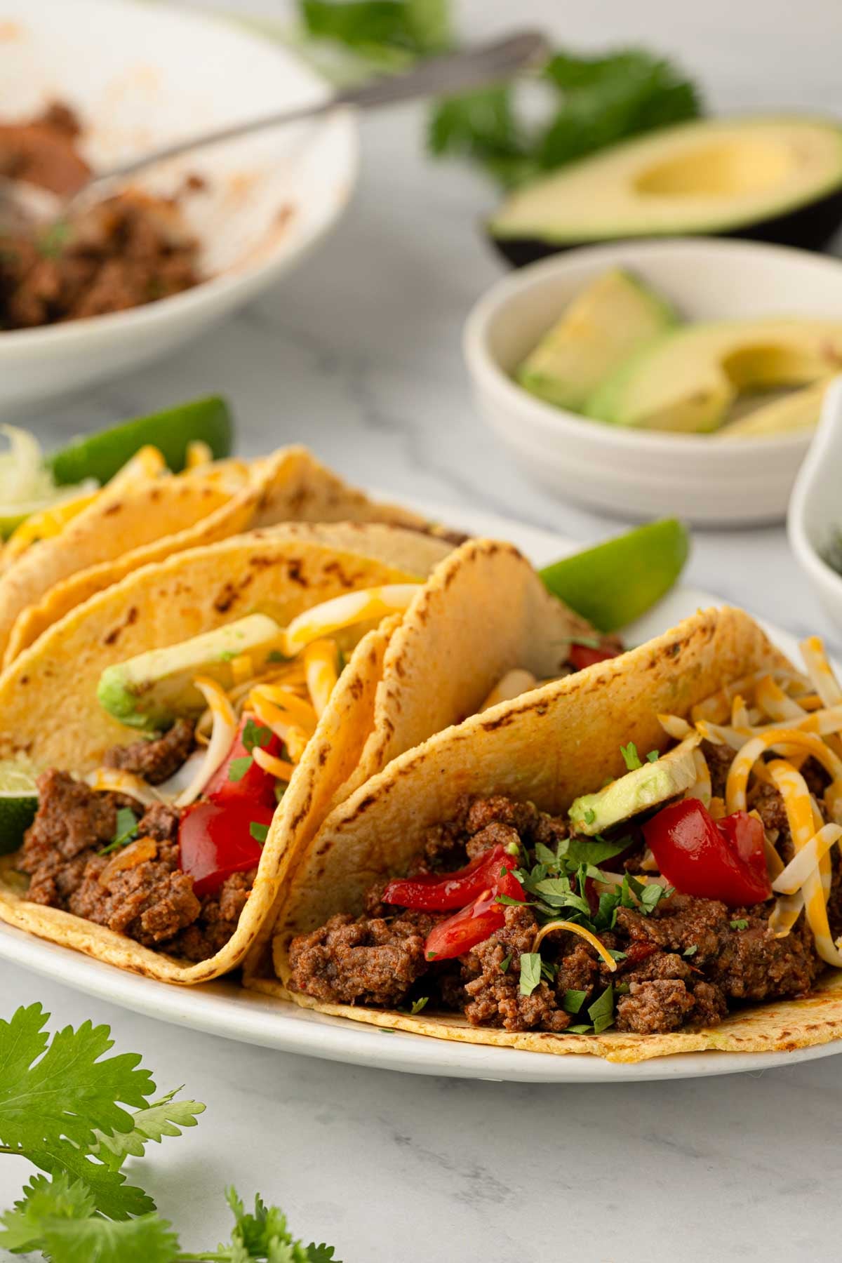 Close up image of slow cooker ground beef tacos on a white platter.